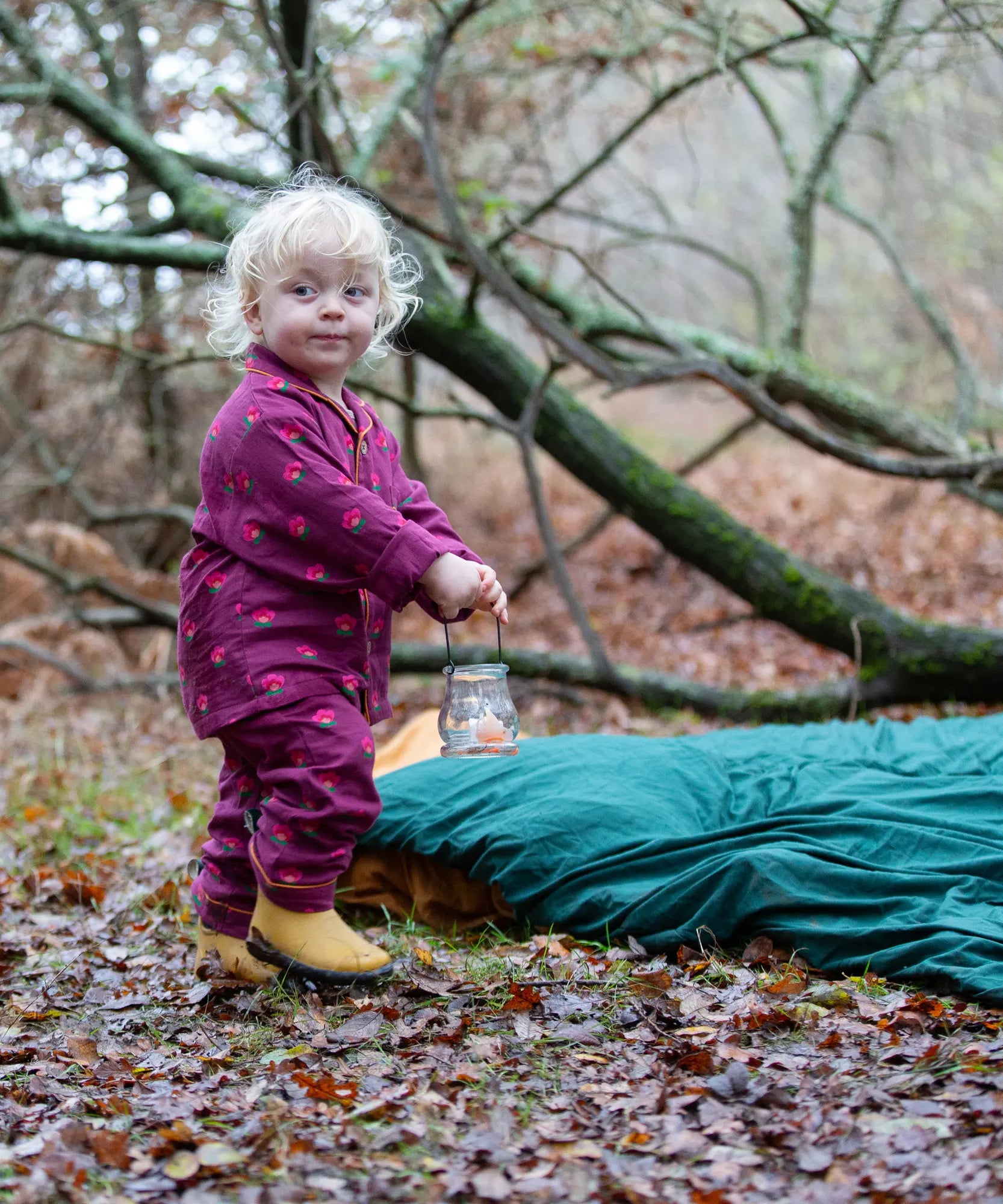 Child wearing the Little Green Radicals pink flowers organic cotton classic pyjamas with yellow gold wellingtons.