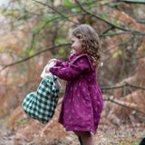 Child wearing the Little Green Radicals pink flowers sailor dress in purple with green wellington boots. 