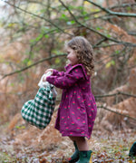Child wearing the Little Green Radicals pink flowers sailor dress in purple with green wellington boots. 