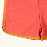 Close up of the yellow gold binding on the Little Green Radicals kids pink sunset recycled swim shorts