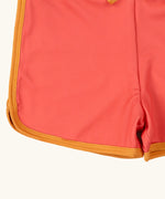 Close up of the yellow gold binding on the Little Green Radicals kids pink sunset recycled swim shorts