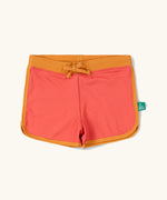 Little Green Radicals pink sunset recycled swim shorts with yellow gold waist and binding. 