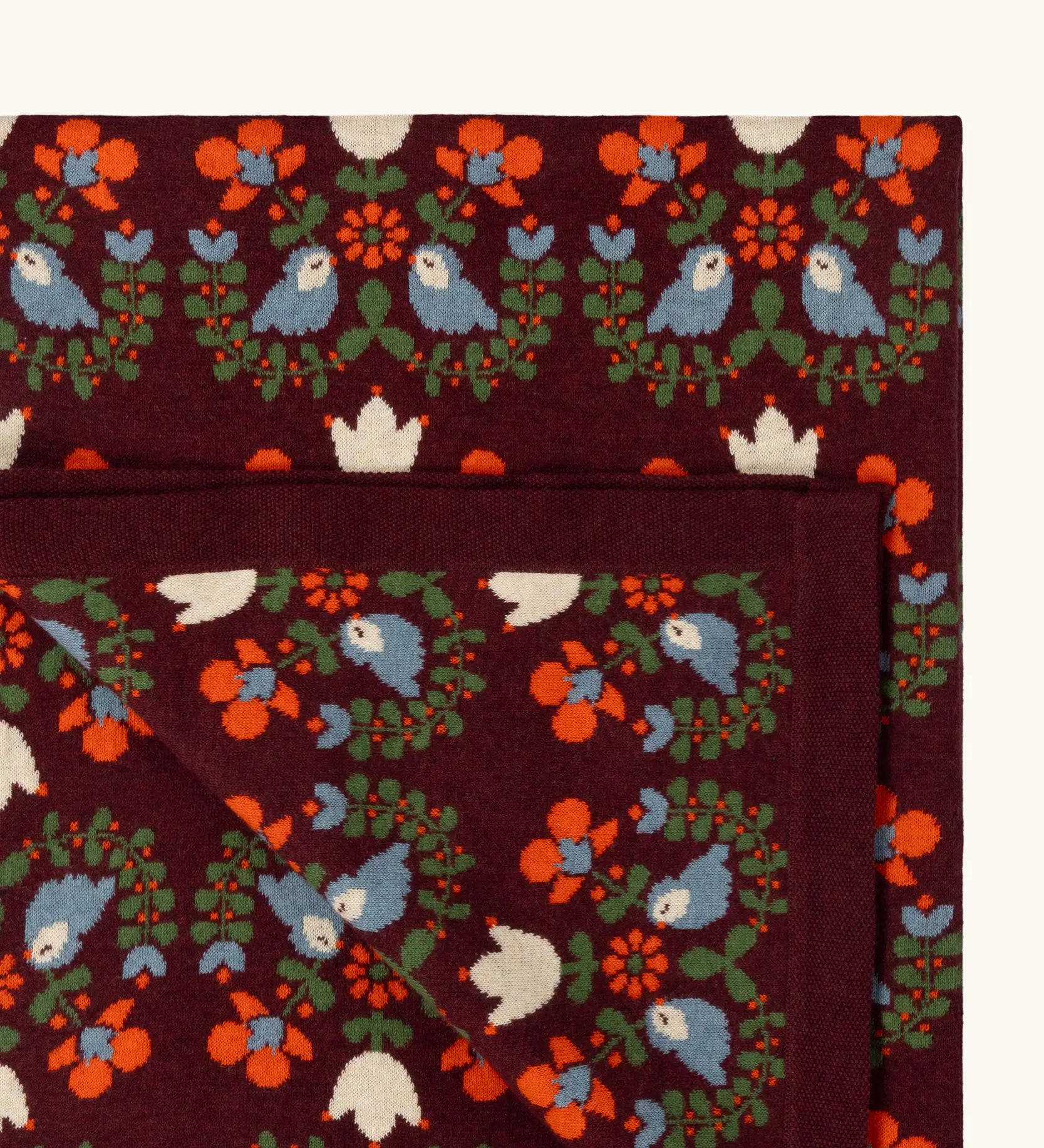 Close up of the Little Green Radicals purple folk birds knitted organic cotton baby blanket. 