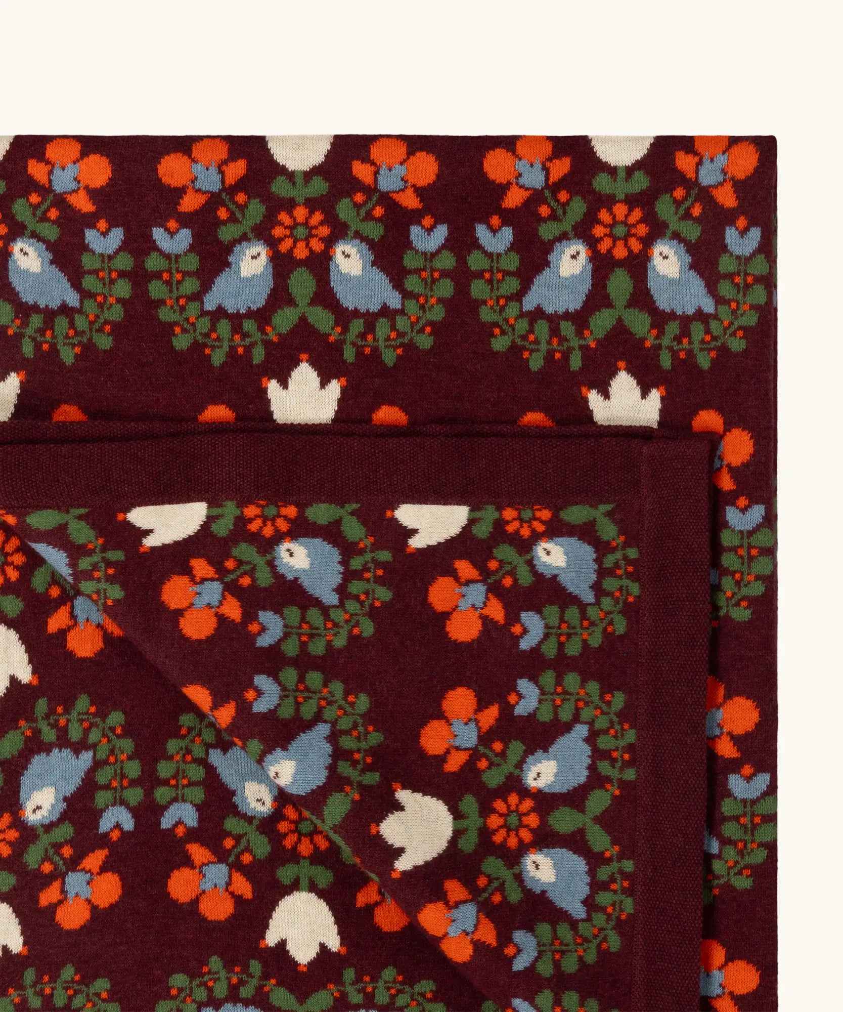 Close up of the Little Green Radicals purple folk birds knitted organic cotton baby blanket. 