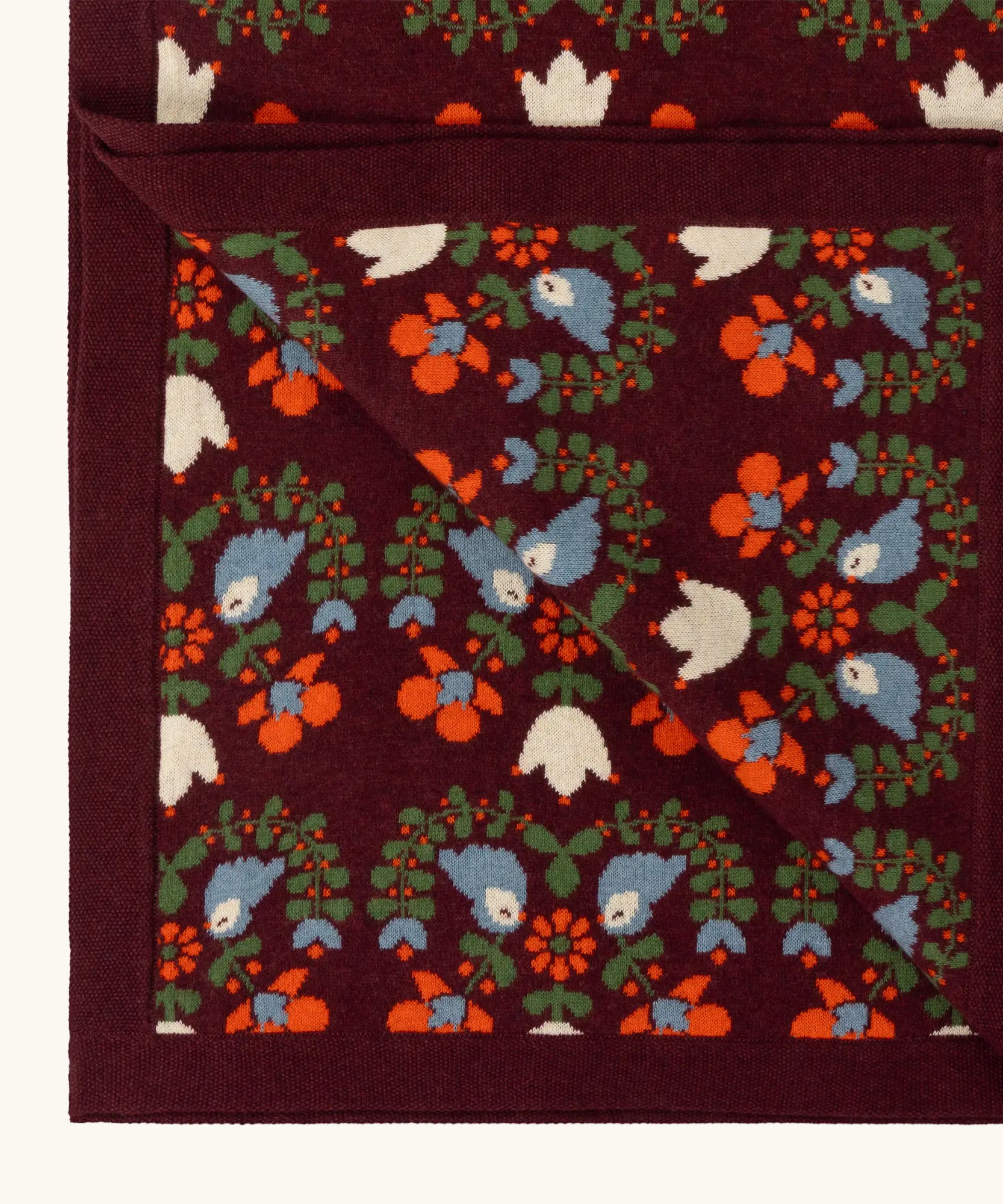 Close up of the Little Green Radicals purple folk birds knitted organic cotton baby blanket. 
