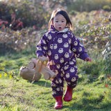 Child wearing the Little Green Radicals purple sleeping swans print sherpa lined snowsuit with red wellington boots.