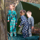 Children standing outside a tent in the forest. They are all wearing Little Green Radicals organic cotton pyjamas. One is wearing a pair with the Winter Rabbit on them, one in wearing navy and white striped design and the third is wearing the sleeping sheep print. Little green Radicals have a wide range of organic cotton, Fairtrade children's clothing an outerwear available here at Babipur.