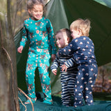 Children standing outside a tent in the forest. They are all wearing Little Green Radicals organic cotton Fairtrade pyjamas. One is wearing a pair with the Winter Rabbit on them, one in wearing navy and white striped design and the third is wearing the sleeping sheep print. Little green Radicals have a wide range of organic cotton, Fairtrade children's clothing an outerwear available here at Babipur.