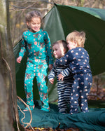 Children standing outside a tent in the forest. They are all wearing Little Green Radicals organic cotton Fairtrade pyjamas. One is wearing a pair with the Winter Rabbit on them, one in wearing navy and white striped design and the third is wearing the sleeping sheep print. Little green Radicals have a wide range of organic cotton, Fairtrade children's clothing an outerwear available here at Babipur.