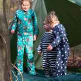 Children standing outside a tent in the forest. They are all wearing Little Green Radicals organic ccotton pyjamas. One is wearing a pair with the Winter Rabbit on them, one in wearing navy and white striped design and the third is wearing the sleeping sheep print. Little green Radicals have a wide range of organic cotton, Fairtrade children's clothing an outerwear available here at Babipur.