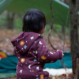 A view of the back of a child wearing the Little Green Radicals Organic Cotton Flying Birds Quilted Snug Suit. A maroon brown coloured suit with an all over print featuring flying birds, stars, moon and  sun. This snug suit is a part of a wide range of organic cotton clothing for children available here at Babipur. 