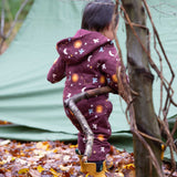 A child wearing the Little Green Radicals Organic Cotton Flying Birds Quilted Snug Suit. A maroon brown coloured suit with an all over print featuring flying birds, stars, moon and  sun. This snug suit is a part of a wide range of organic cotton clothing for children available here at Babipur. 