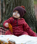 A baby wearing the Little Green Radicals Organic Cotton Quilted Snug Suit with a Red Stars design. This snug suit is a part of a wide range of organic cotton clothing for children available here at Babipur. 