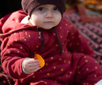 A baby wearing the Little Green Radicals Organic Cotton Quilted Snug Suit with a Red Stars design. This snug suit is a part of a wide range of organic cotton clothing for children available here at Babipur. 