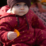 A baby wearing the Little Green Radicals Organic Cotton Quilted Snug Suit with a Red Stars design. This snug suit is a part of a wide range of organic cotton clothing for children available here at Babipur. 