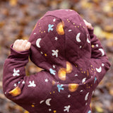A close up of the hood with a child wearing the Little Green Radicals Organic Cotton Flying Birds Quilted Snug Suit. A maroon brown coloured suit with an all over print featuring flying birds, stars, moon and  sun. This snug suit is a part of a wide range of organic cotton clothing for children available here at Babipur. 
