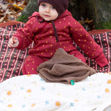A baby wearing the Little Green Radicals Organic Cotton Quilted Snug Suit with a Red Stars design. This snug suit is a part of a wide range of organic cotton clothing for children available here at Babipur. 