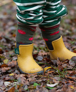 Child wearing the Little Green Radicals red apple terry boot socks with yellow gold wellington boots. 