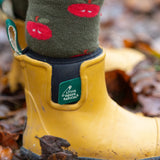 Close up of child wearing the Little Green Radicals red apple terry boot socks with yellow gold wellington boots. 