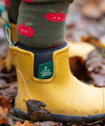 Close up of child wearing the Little Green Radicals red apple terry boot socks with yellow gold wellington boots. 