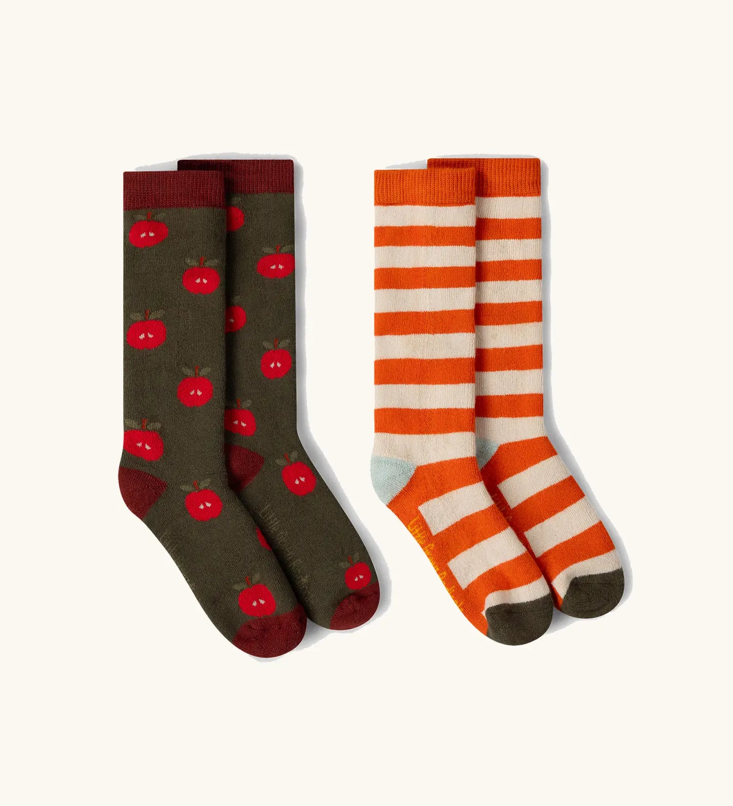 Little Green Radicals red apple organic cotton boot socks in a 2 pack. One dark green pair with red apple print, one white and orange stripes.