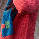 Close up of child wearing Little Green Radicals tulips knitted blue scarf. Blue scarf with red tulips.