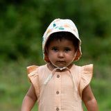 Child wearing the Little Green Radicals organic cotton reversible sunhat on the flora pink and yellow flowers print side.