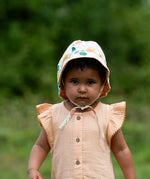 Child wearing the Little Green Radicals organic cotton reversible sunhat on the flora pink and yellow flowers print side.