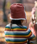 A child wearing the Little Green Radicals Ginger orange coloured Children's Sherpa Fleece Cosy Hat. This hat is a part of a wide range of organic cotton clothing and accessories for children available here at Babipur. 