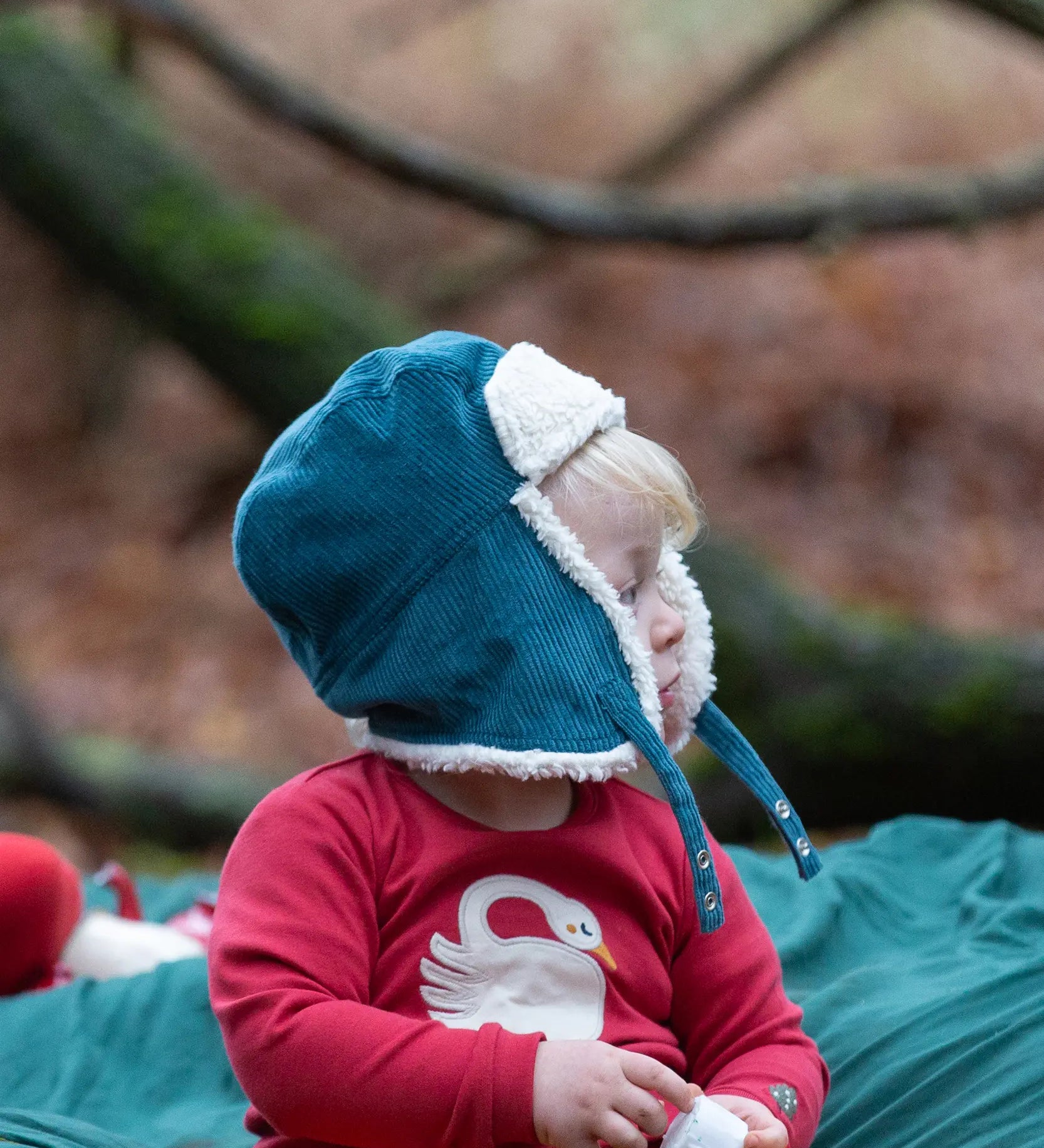 Baby wearing the Little Green Radicals sherpa fleece lined blue corduroy cosy hat.