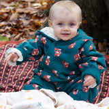 A baby wearing the Little Green Radicals Sherpa Fleece Snowsuit , a Organic Cotton suit with a Red Foxes all over print on a dark green background. This lined snowsuit is a part of a wide range of organic cotton clothing for children available here at Babipur. 