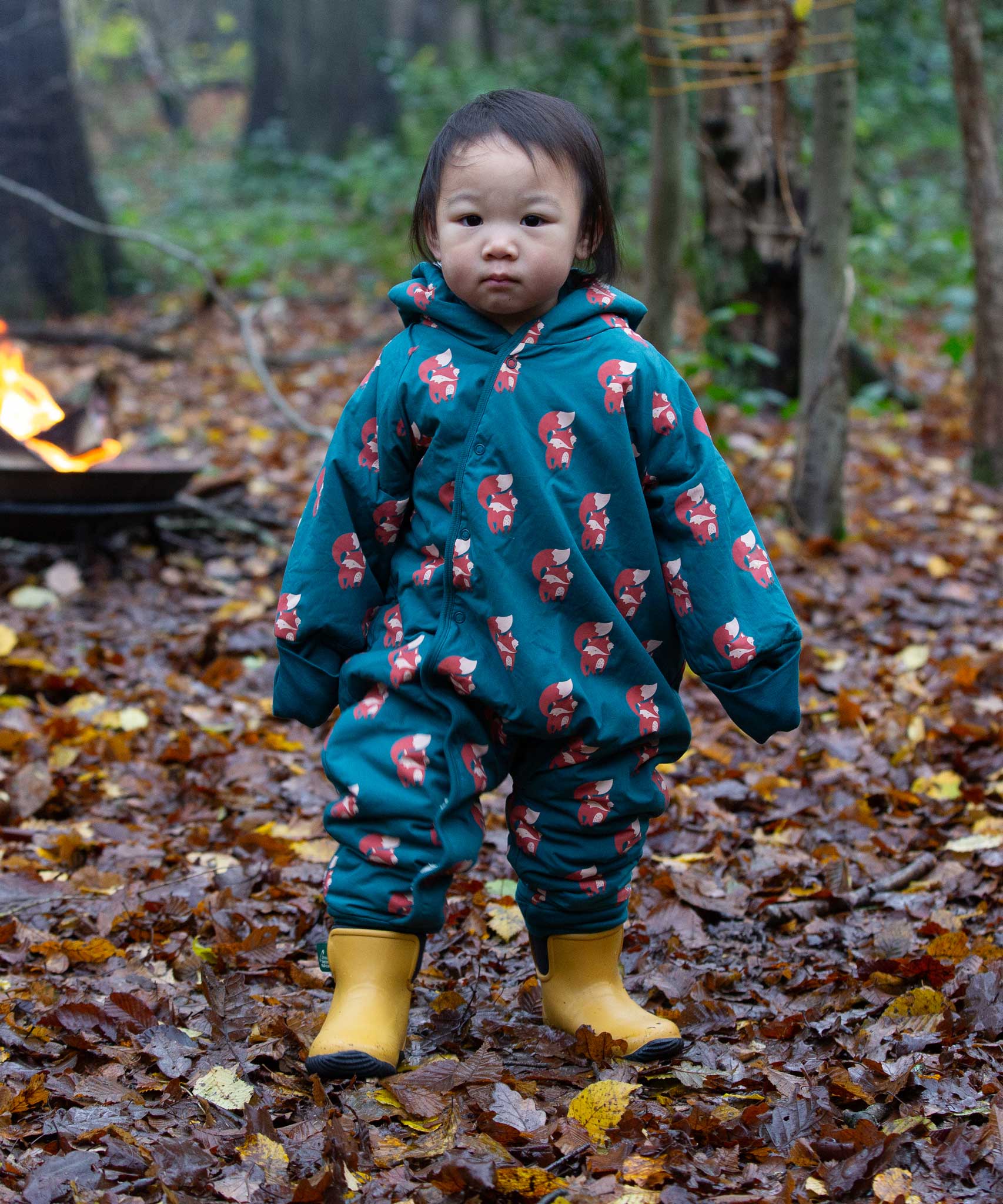 A child wearing the Little Green Radicals Sherpa Fleece Snowsuit , a Organic Cotton suit with a Red Foxes all over print on a dark green background. This lined snowsuit is a part of a wide range of organic cotton clothing for children available here at Babipur. 
