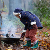 A child wearing the Little Green Radicals Kids Dark Night design Organic Sherpa lined Toasty Coat. This warm coat is navy with a yellow moon and stars print all over with a white sherpa fleece lining. This coat is a part of a wide range of organic cotton clothing for children available here at Babipur. 