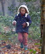 A child wearing the Little Green Radicals Kids Dark Night design Organic Sherpa lined Toasty Coat. This warm coat is navy with a yellow moon and stars print all over with a white sherpa fleece lining. This coat is a part of a wide range of organic cotton clothing for children available here at Babipur. 
