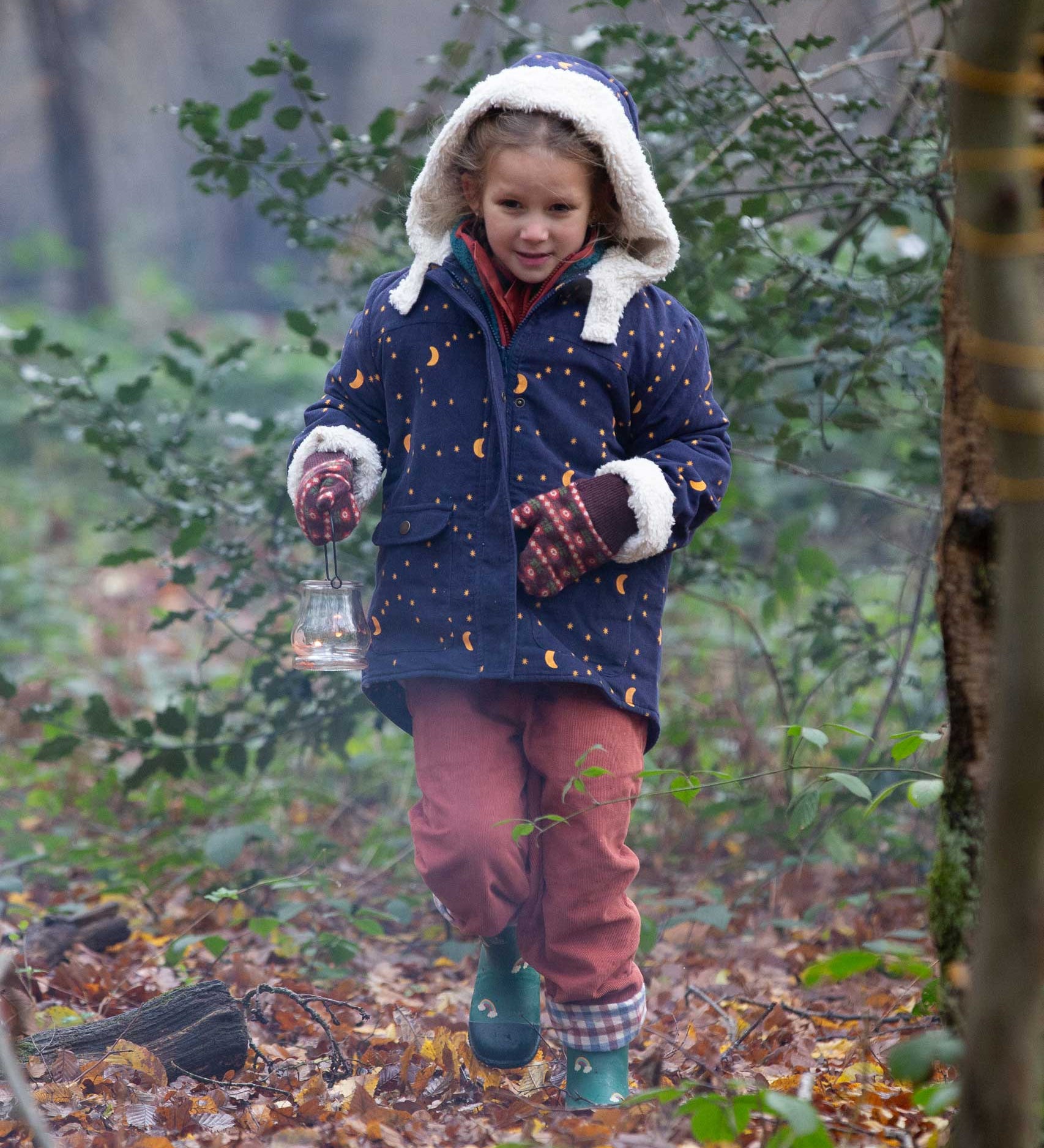 A child wearing the Little Green Radicals Kids Dark Night design Organic Sherpa lined Toasty Coat. This warm coat is navy with a yellow moon and stars print all over with a white sherpa fleece lining. This coat is a part of a wide range of organic cotton clothing for children available here at Babipur. 
