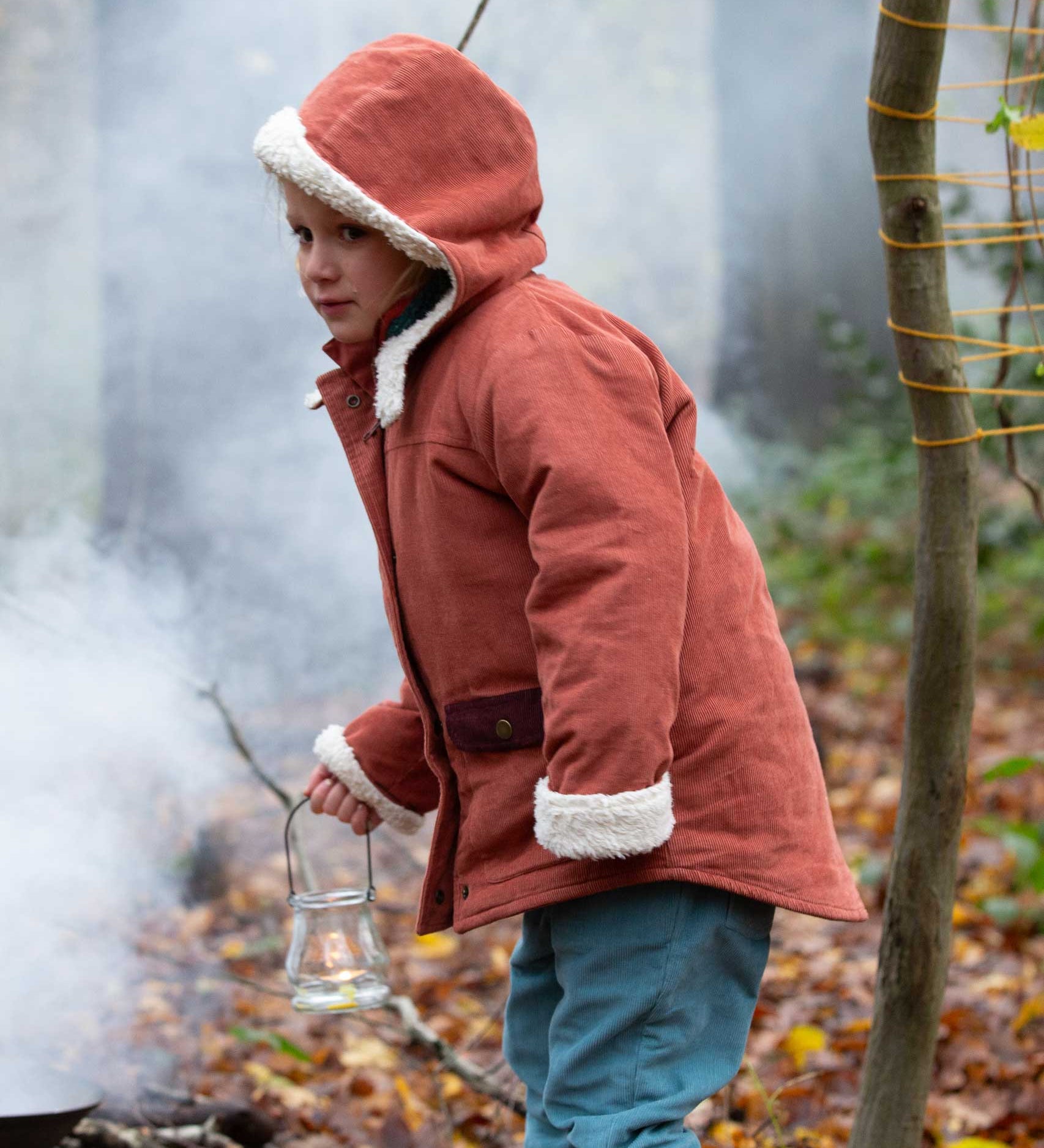 A child wearing the Little Green Radicals Kids Organic Sherpa Toasty Coat in a ginger colourway. This warm orange coloured jacket is part of a wide range of organic cotton clothing for children available here at Babipur. 