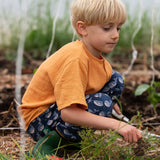Child wearing the Little Green Radicals navy singing whales print comfy organic cotton joggers with a yellow muslin henley t-shirt.