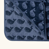 Little Green Radical hooded towel in navy blue with a repeating whale design showing contrast inner lining 