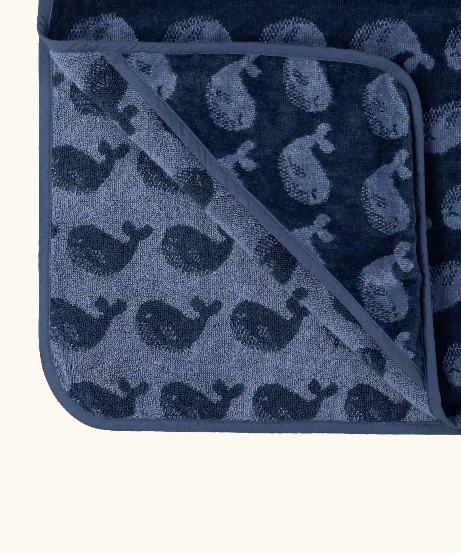 Little Green Radical hooded towel in navy blue with a repeating whale design showing contrast inner lining 