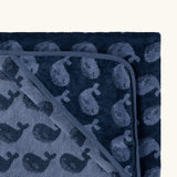 Top corner of Little Green Radicals GOTS organic cotton hooded towel in navy blue with a repeating whale design