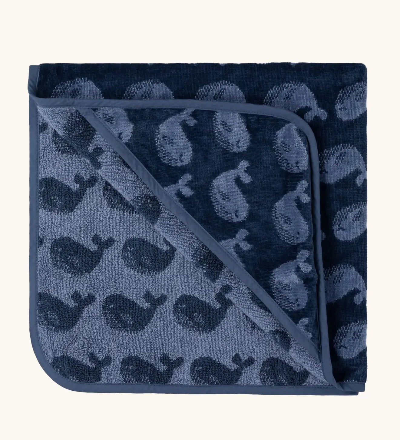Little Green Radicals GOTS organic cotton hooded towel in navy blue with a repeating whale design folded into a square