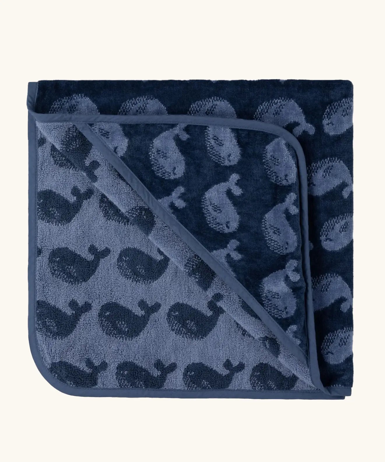 Little Green Radicals GOTS organic cotton hooded towel in navy blue with a repeating whale design folded into a square