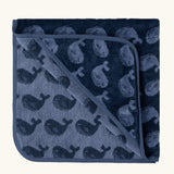 Little Green Radicals GOTS organic cotton hooded towel in navy blue with a repeating whale design folded into a square