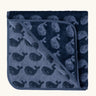 Little Green Radicals GOTS organic cotton hooded towel in navy blue with a repeating whale design folded into a square