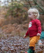 Child wearing the Little Green Radicals sleeping swan applique long sleeve organic cotton top in red with yellow gold joggers.