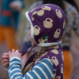 Child wearing a Little Green Radicals  sleeping swans print sherpa fleece lined purple hat.