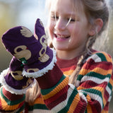 Child wearing Little Green Radicals  sleeping swans print sherpa fleece lined purple mittens with a rainbow striped knitted jumper.