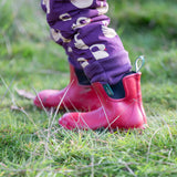 Close up of the leg cuffs on the Little Green Radicals purple sleeping swans print sherpa lined snowsuit worn by a child with red wellington boots.