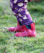 Close up of the leg cuffs on the Little Green Radicals purple sleeping swans print sherpa lined snowsuit worn by a child with red wellington boots.