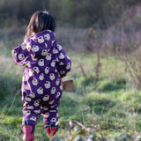 Child wearing the Little Green Radicals purple sleeping swans print sherpa lined snowsuit with red wellington boots. View of back of suit showing hood down.